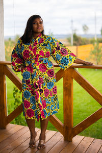 Portrait of young woman standing against railing