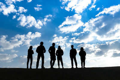 Silhouette people standing on land against sky