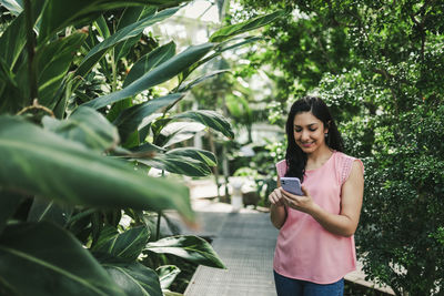 Beautiful girl checking her cell phone in the greenhouse