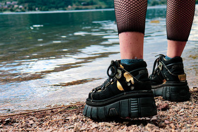 Low section of person standing by lake