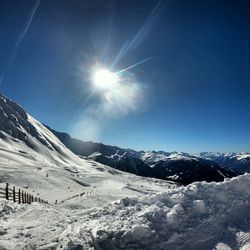 Scenic view of snowcapped mountains against bright sun