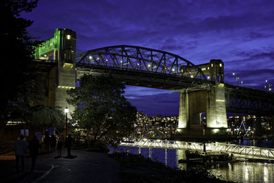 Illuminated bridge over river at night