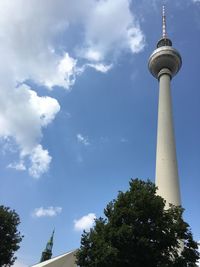 Low angle view of communications tower against cloudy sky