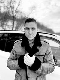 Portrait of man wearing sunglasses standing against car