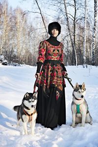 Woman wearing traditional costume with siberian huskies on snowy field