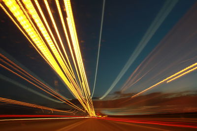 Light trails on road against sky at night