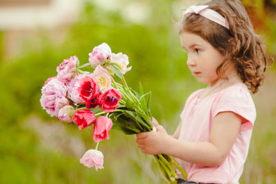 Cute girl holding tulip while standing outdoors