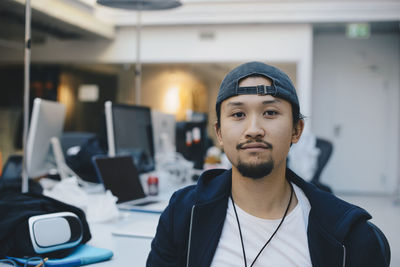 Portrait of confident computer programmer wearing cap in office