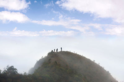 People standing by tree against sky