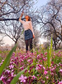 Full length of woman standing by flowering plants on field