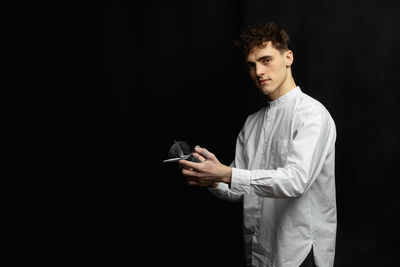 Portrait of male hairdresser with scissor by black background