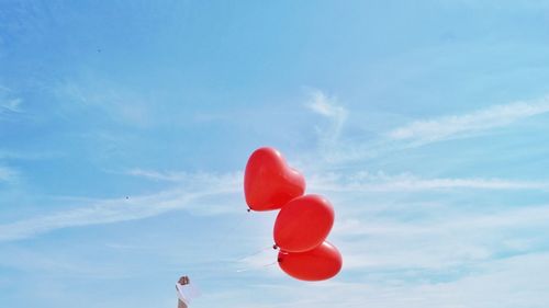 Low angle view of heart shaped balloons against sky