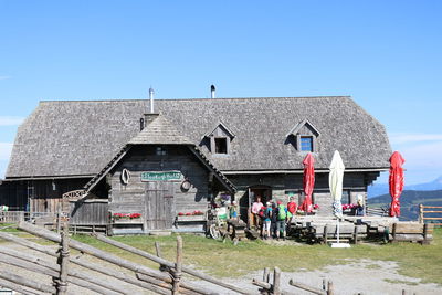 People on field by building against clear blue sky