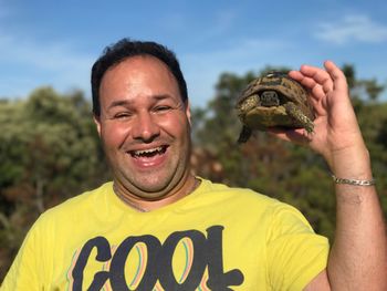 Portrait of smiling man holding turtle