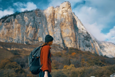 Rear view of man standing on mountain against sky