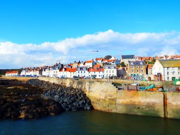 Houses by pittenweem harbor against sky