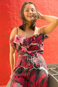 Portrait of young woman against red wall