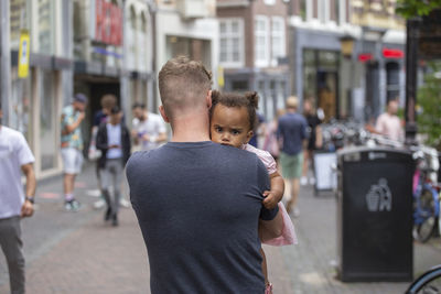 A caucasian father carries his daughter through the streets of utrecht