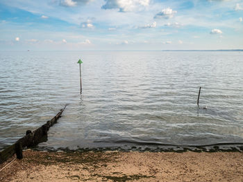 Horizon over water on the beach at shoeburyness with groynes and green markers