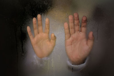 Close-up of hand on wet glass in bathroom