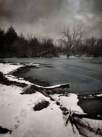 Snow covered landscape against cloudy sky