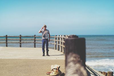 Rear view of woman standing on railing against sea