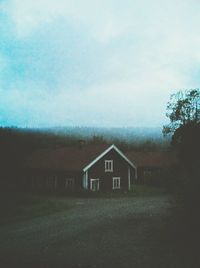 Houses on field against cloudy sky