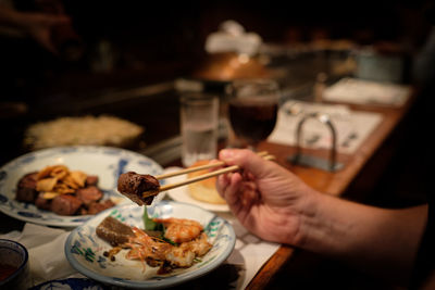 Cropped image of hand having food at restaurant