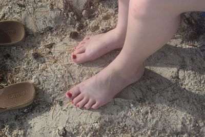 Low section of man relaxing on sand at beach