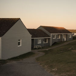 Houses by street against clear sky during sunset