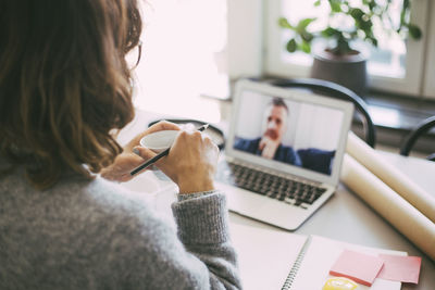 Woman in home office having online meeting with coworker