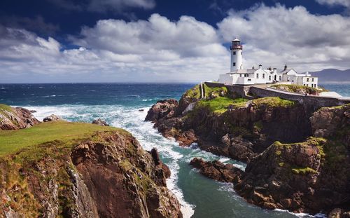 Lighthouse by sea against sky