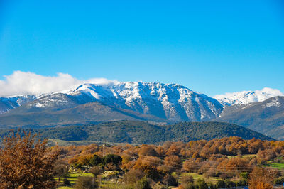 Scenic view of snowcapped mountains against blue sky