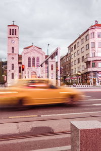 Blurred motion of city street and buildings against sky