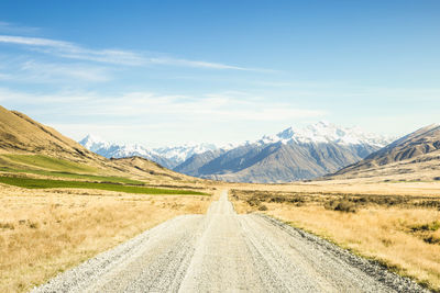 Road leading towards mountains against sky