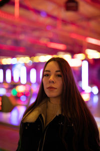 Portrait of beautiful woman standing against illuminated lights