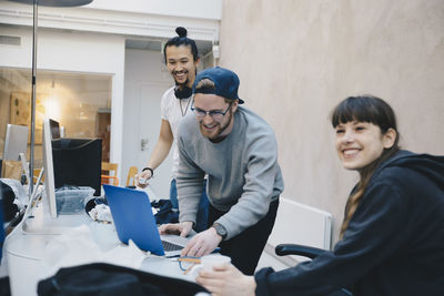 Happy male and female computer programmers at desk in office