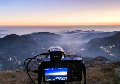 View of camera on mountains against sky during sunset