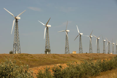 Windmills on field against sky