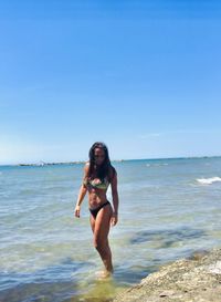 Full length of young woman at beach against clear sky
