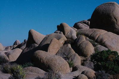 Low angle view of rocks against clear blue sky