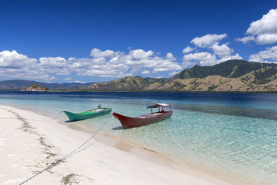 Boat moored on beach against blue sky