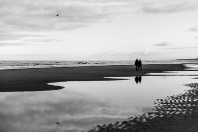 Silhouette man on beach against sky