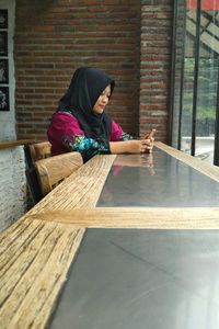 Woman using phone while sitting at table