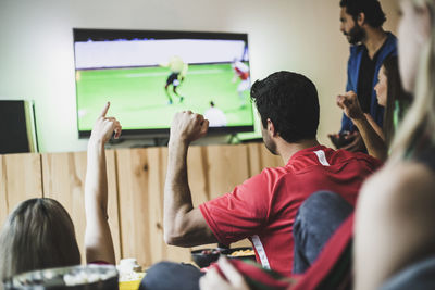 Male and female friends watching soccer match on tv at home