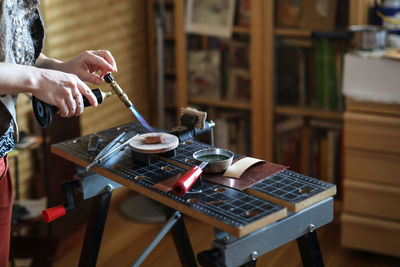 The master woman near the bench works with tools, on the torch boils water with a metal plate. 