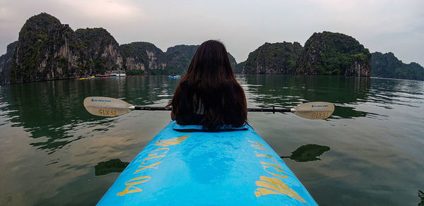 Rear view of woman on boat in lake against sky