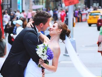 Side view new married couple embracing on city street