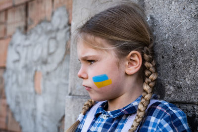 Cute girl with face paint by wall