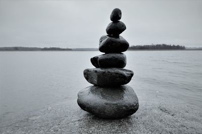 Stack of stones on rock at beach against sky - zen tile.